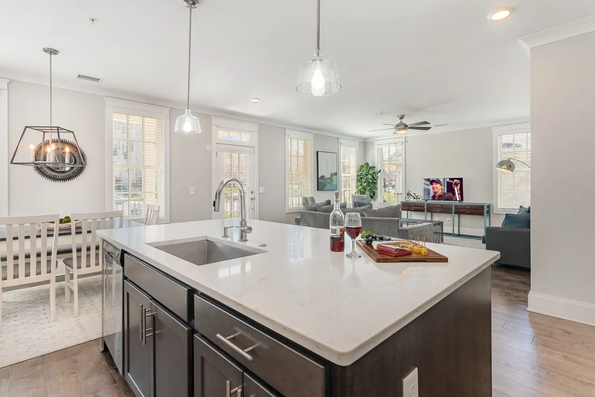 This image captures an open-concept main living area, seamlessly blending the kitchen island, dining area, and a comfortable living room with plush seating and a television. The modern design and layout foster a sense of togetherness, ideal for group gatherings and shared experiences.