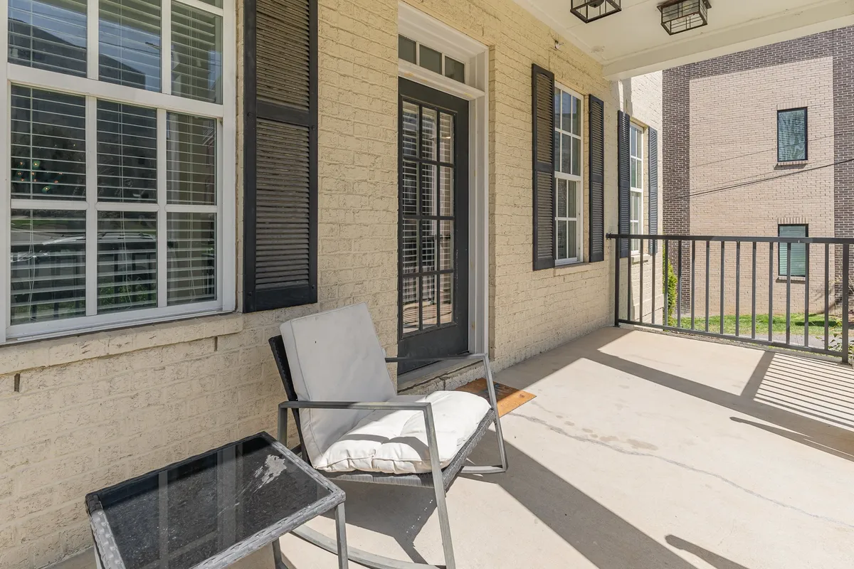 A cozy porch view with a chair, small table, and a glimpse of the doorway and windows, suggesting an intimate entryway space perfect for reading or sipping coffee as the day begins.